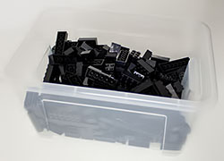 Ikea© plastic box filled with black Lego® bricks